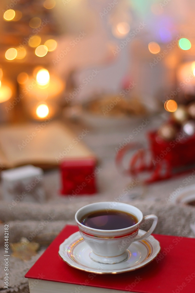 Bowl of cookies, cup of tea, dry oranges, pine cones, books, reading glasses, small presents, various Christmas decorations and lit candles on the table. Cozy Christmas hygge. Selective focus. Bowl of cookies, cup of tea, dry oranges, pine cones, books, reading glasses, small presents, various Christmas decorations and lit candles on the table. Cozy Christmas hygge. Selective focus.