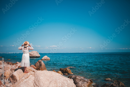 Chic woman in a dress, Turkish coastline, embodying travel elegance by the serene sea