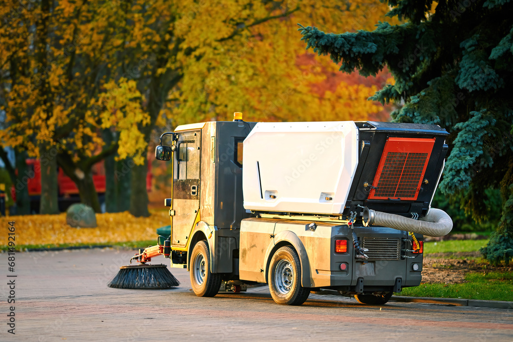 Street sweeper machine cleaning street from fallen leaves and dust, vacuum cleaner. Vehicle sweeping streets, cleaning up sidewalk. Road sweeper