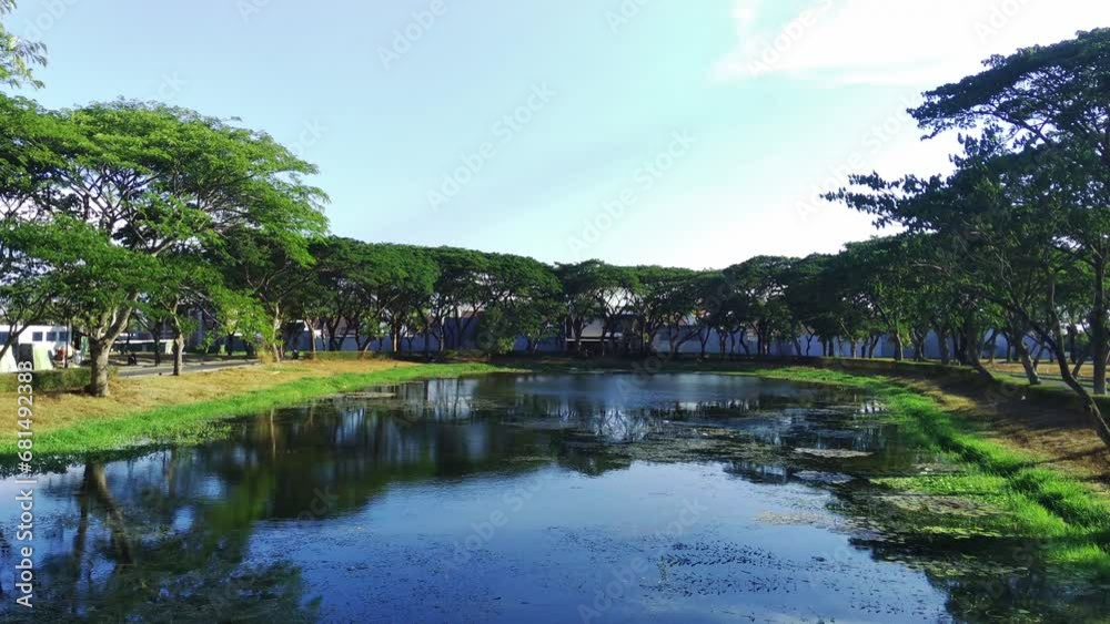 Low flight of Drone flying above a river surrounded by trees on a sunny day in Surabaya, Indonesia. Low flight of Drone flying above a river surrounded by trees on a sunny day in Surabaya, Indonesia.