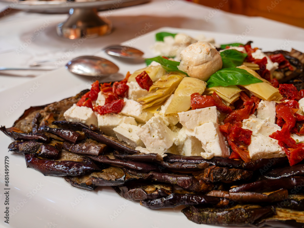 An Mediterranean plate featuring feta cheese, bell peppers, artichokes, mushrooms, and aubergines An Mediterranean plate featuring feta cheese, bell peppers, artichokes, mushrooms, and aubergines