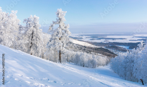 Aerial view in winter time from the top of the hill. Snow covered slope and trees on the hill in Russia