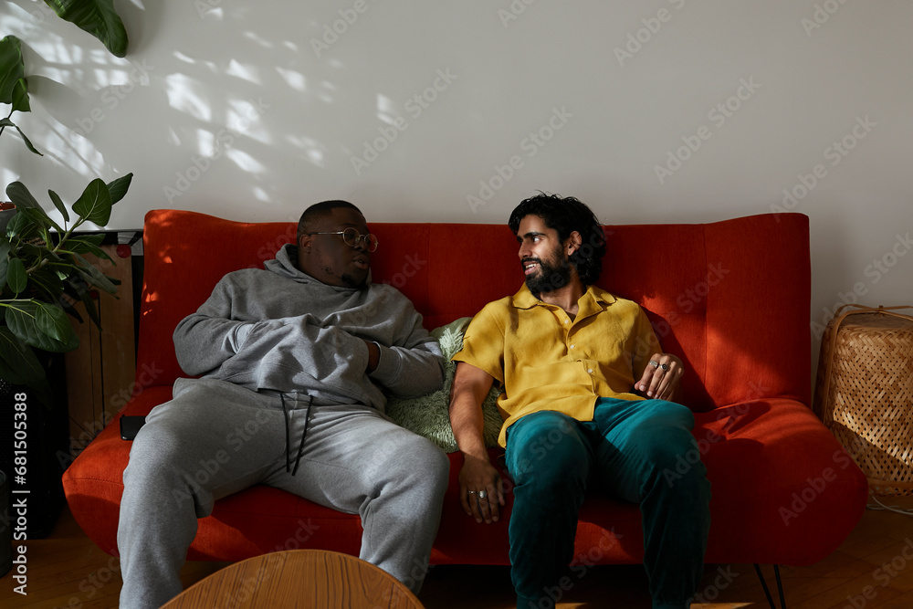 Two male friends lounging on sofa and having conversation. Concept of gen z, fashion and self expression.