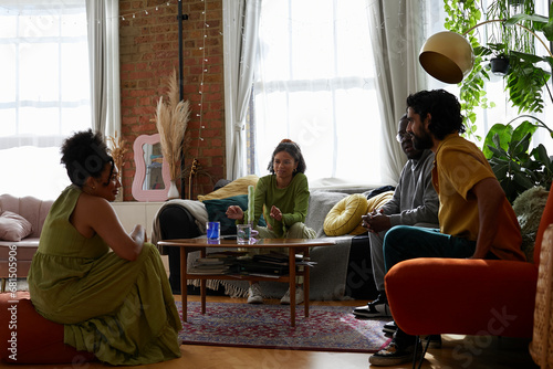 Group of 4 friends sat around coffee table and having conversation. Concept of gen z, fashion and self expression.