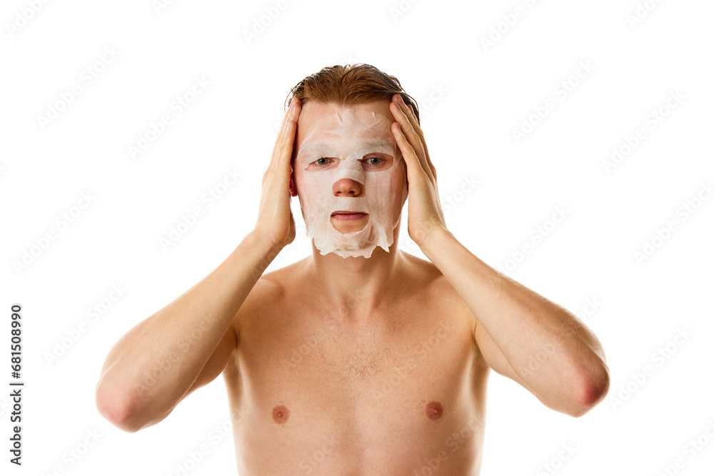 Daily selfcare routine. Male model with red hair applying moisturized, hydrating mask against white studio background. Daily selfcare routine. Male model with red hair applying moisturized, hydrating mask against white studio background.