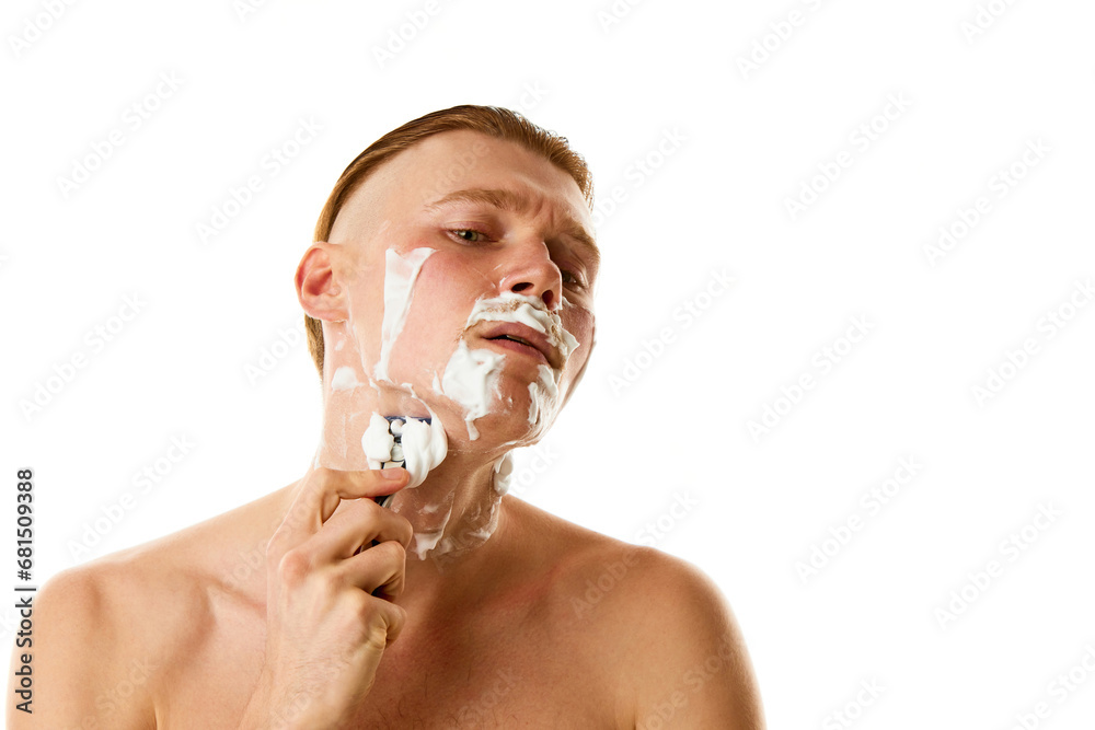 Hygiene treatments. Attractive man shaving beard with shaving foam looking at camera against white studio background.