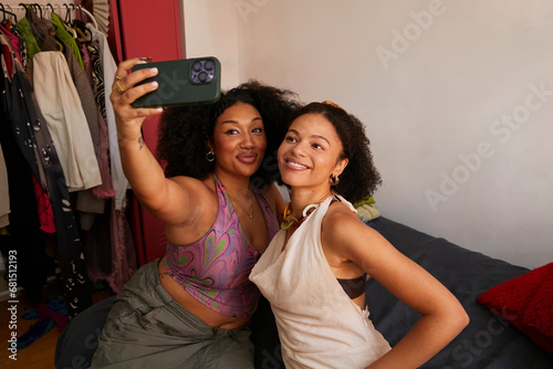 Two biracial women take a selfie together on a mobile phone. Concept of gen z, fashion and self expression.