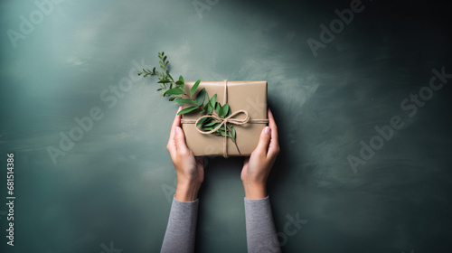 ユーカリを後ろに飾って、植物を使ったナチュラルなラッピングしたプレゼントを手包んでいるアップの写真、背景グレー photo