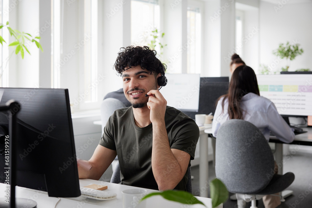 Man wearing headset using desktop PC in office Man wearing headset using desktop PC in office