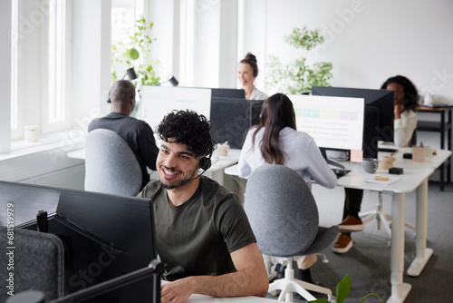 Man wearing headset using desktop PC in office photo