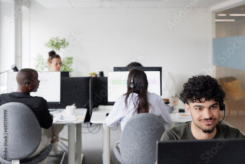 Man wearing headset using desktop PC in office photo
