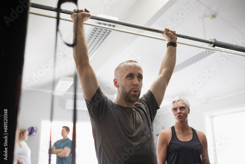Mid adult man lifting barbell pole in gym photo