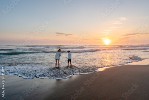 Kids playing in sea at sunset