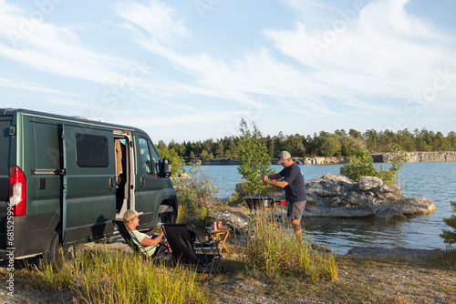 Couple relaxing next to camper van at lakeshore photo
