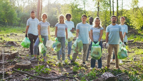 Eco volunteers smiling and standing in park. Group of diverse people holding bin bags full of trash. Multiracial, Volunteering, global concern concept