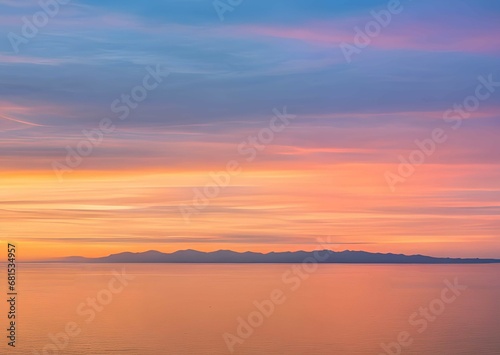 穏やかな湖面：オレンジ、ピンク、青のグラデーションが広がる空と、その色が静かな湖面に反射し、地平線は山々のシルエットで描かれている、日の出または日没の風景 © sky studio