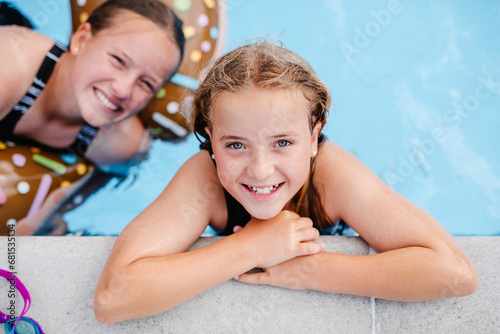 High angle portrait of smiling girl leaning at poolside with sister photo