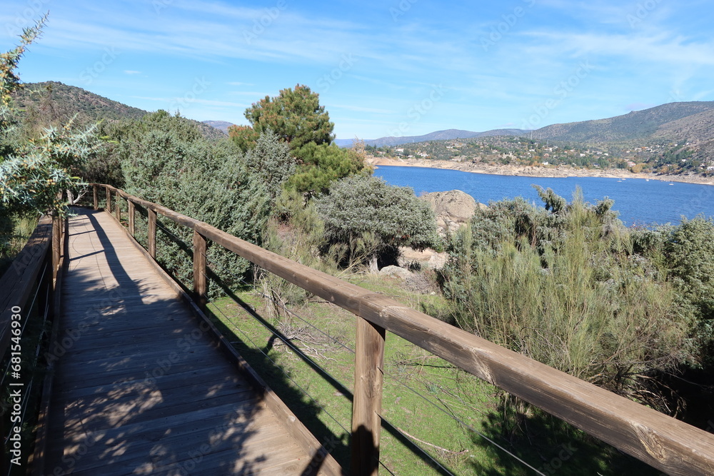 El Burguillo Reservoir, Avila, Spain, November 13, 2023: El Enebral Trail. Wooden walkway on one of the banks of the El Burguillo Reservoir, Avila, Spain