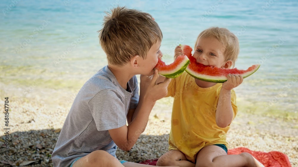 Two funny boys sitting on the beach and having fun with watermelon rinds after eating at the sea. Two funny boys sitting on the beach and having fun with watermelon rinds after eating at the sea.