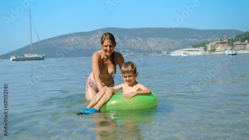 Happy smiling mother with son swimming in inflatable swimming ring at the sea beach. Family holiday, vacation and fun summertime of children and parents. © Кирилл Рыжов