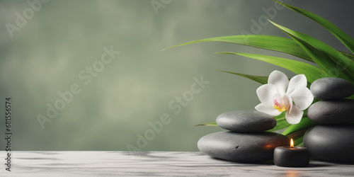 Zen stones, candles and white orchid flower on green and grey background with copy space, wellness and harmony, massage, spa and bodycare concept