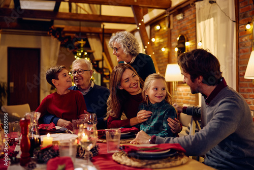 Happy multigeneration family communicating while gathering at dining table on Christmas Eve.