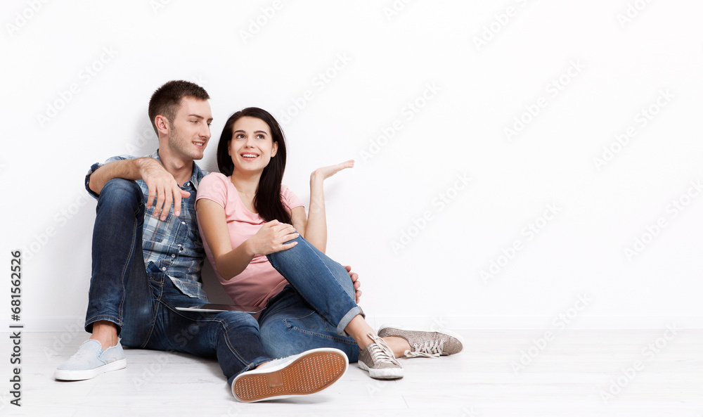 Happy young couple sitting on floor looking up while dreaming their new home and furnishing. Mock up Happy young couple sitting on floor looking up while dreaming their new home and furnishing. Mock up
