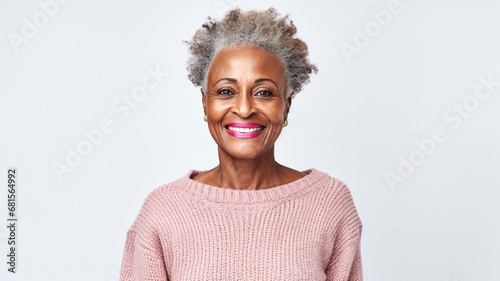 Happy black senior woman wearing cosy sweater in a studio shoot standing against grey background.

 photo