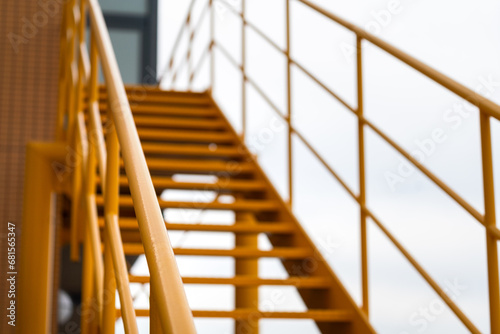 Banister handril with yellow painting of stairway platform at the factory place. Industrial building structure part photo, Close-up and selective focus at handrail. photo