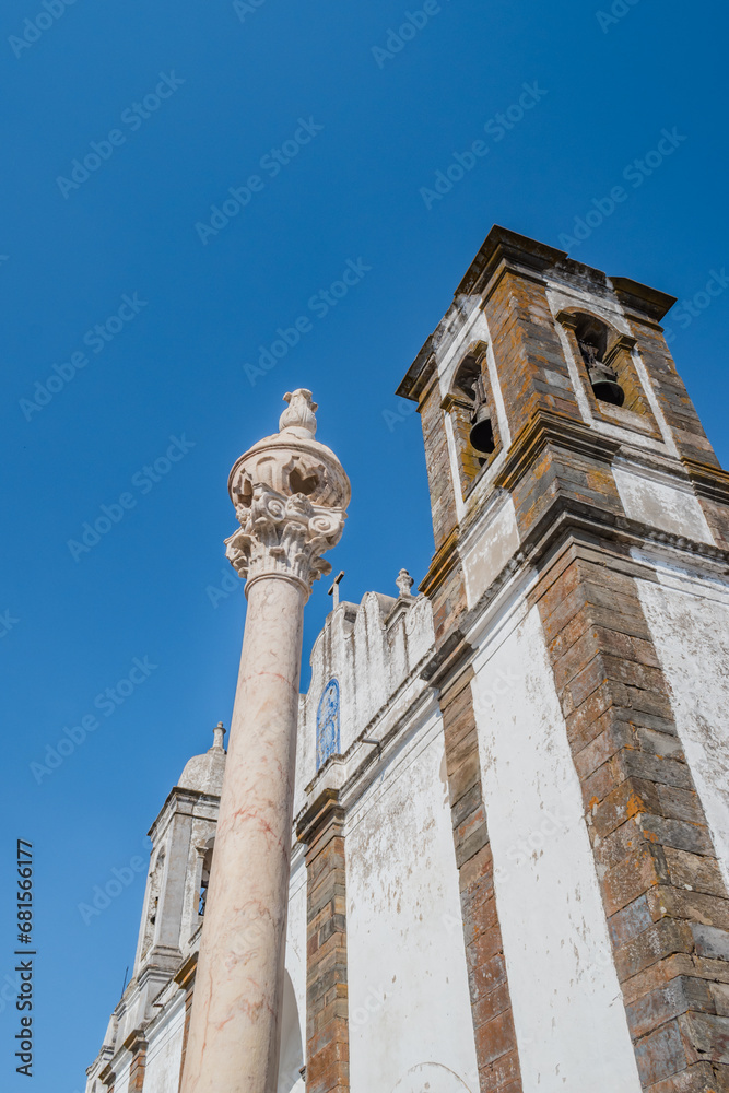 Perspective of Monsaraz marble pillory and bell towers on the facade of Our Lady of Lagoa church, Alentejo PORTUGAL