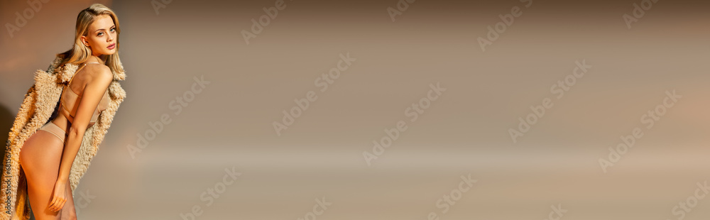 Fototapeta premium attractive blonde woman in beige sexy lingerie and faux fur bending her body slightly, banner
