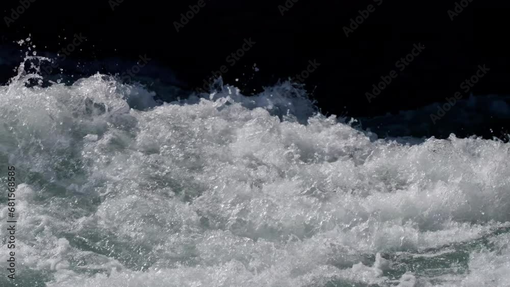 slow-motion shooting of splashes and drops of water in a fast mountain river close-up. bright light in the foreground, shadow in the background slow-motion shooting of splashes and drops of water in a fast mountain river close-up. bright light in the foreground, shadow in the background