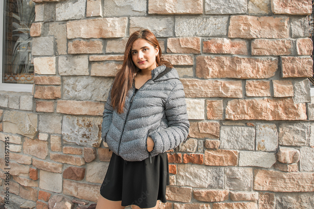 Portrait of diversity young beautiful confident Indian Asian woman in fall season brick building background. Happy and natural smiling female. Generation z and gen z youth concept