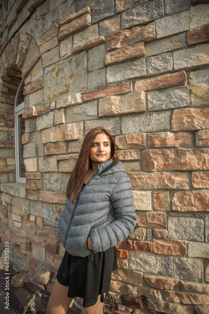 Portrait of diversity young beautiful confident Indian Asian woman in fall season brick building background. Happy and natural smiling female. Generation z and gen z youth concept