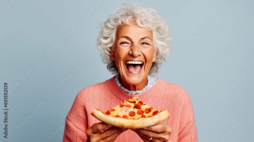 Joyful elderly lady poses with pizza against a studio light blue backdrop. Joyful elderly lady poses with pizza against a studio light blue backdrop.
