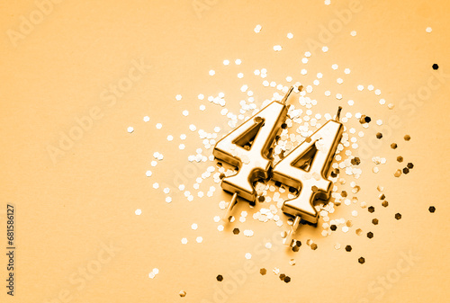 44 years birthday celebration festive background made with golden candle in the form of number Forty four lying on sparkles. photo