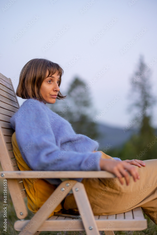 Portrait of a thoughtful woman sitting on wooden chair while resting in the mountains Portrait of a thoughtful woman sitting on wooden chair while resting in the mountains