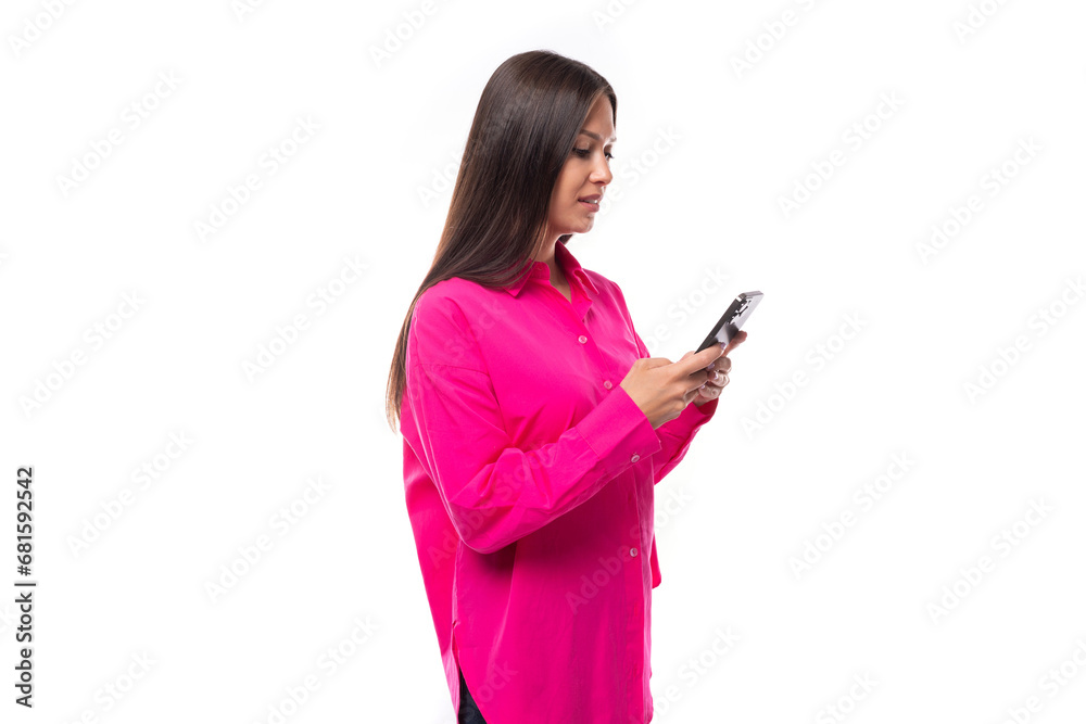 young brunette lady dressed in a bright pink shirt is chatting in a smartphone in a social network young brunette lady dressed in a bright pink shirt is chatting in a smartphone in a social network