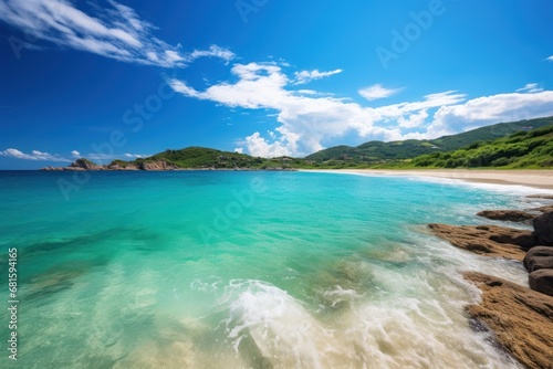  a body of water sitting next to a sandy beach on top of a lush green hillside next to a lush green forest covered hillside on the side of a blue sky with white clouds.
