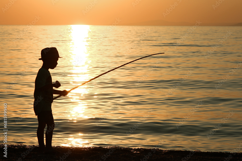 A happy child fishing by the sea silhouette