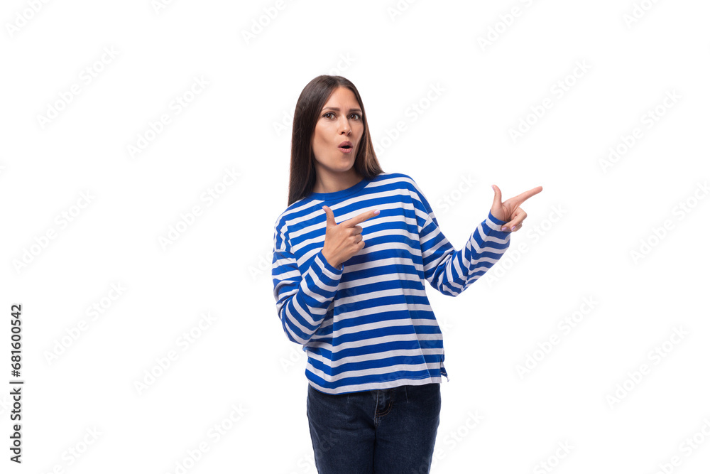 charming young brunette woman in a striped blue sweater points with her hand to the advertising space on a white background with copy space charming young brunette woman in a striped blue sweater points with her hand to the advertising space on a white background with copy space