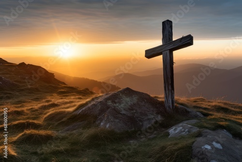  a cross on top of a hill with the sun setting in the distance behind it and a mountain range in the foreground with grass and rocks in the foreground.