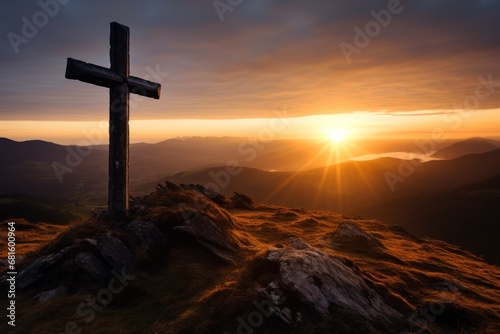  a cross on top of a hill with the sun setting in the distance in the distance in the distance is a mountain range with mountains and a body of water in the foreground.