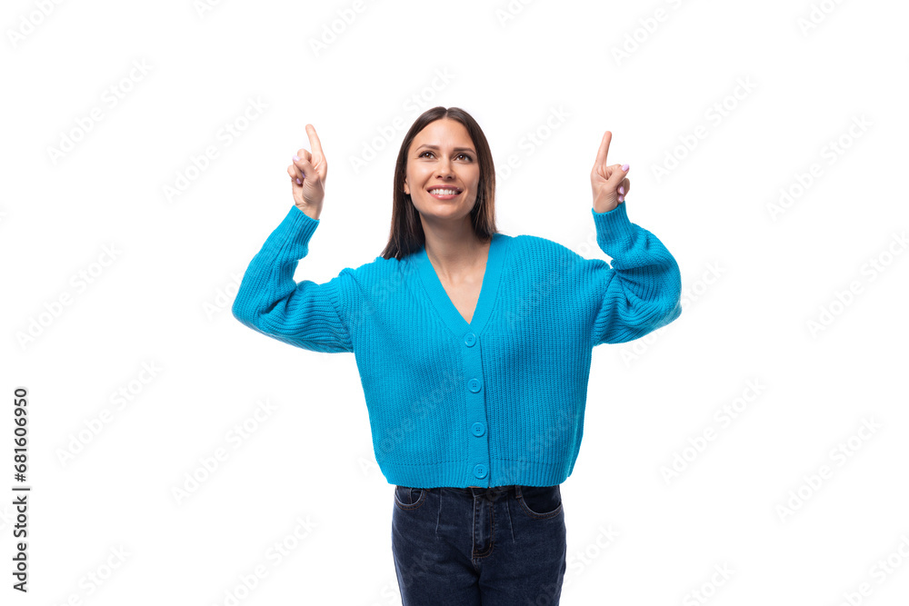 young stylish brunette promoter lady dressed in a blue V-neck sweater shows her hand to the advertising space on a white background with copy space young stylish brunette promoter lady dressed in a blue V-neck sweater shows her hand to the advertising space on a white background with copy space