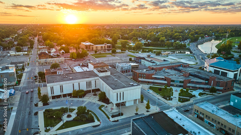 Fototapeta premium Muncie courthouse building in downtown aerial of city with golden sun setting on horizon