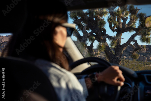 Silhouette of unfocused woman driving his car around Joshua Tree National Park at sunset, California