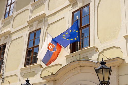 Slovakia flag and EU flag on the wall of a house. Flags in the facade of old building. Slovakia is a member of the European Union and the Eurozone. photo