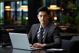 Successful male businessman of Asian appearance in a business suit works at a laptop. Generative AI