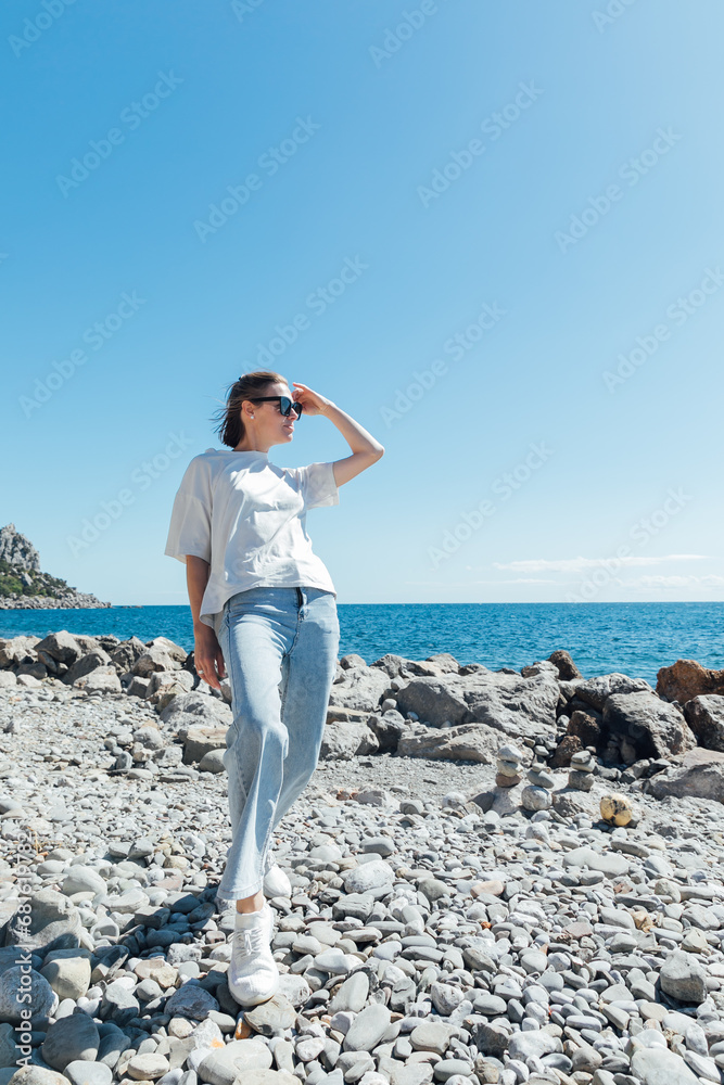 Beautiful slender woman walking on the beach near the seashore