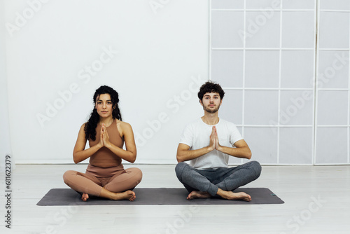 Yoga group concept. Young couple meditating together, sitting back to back